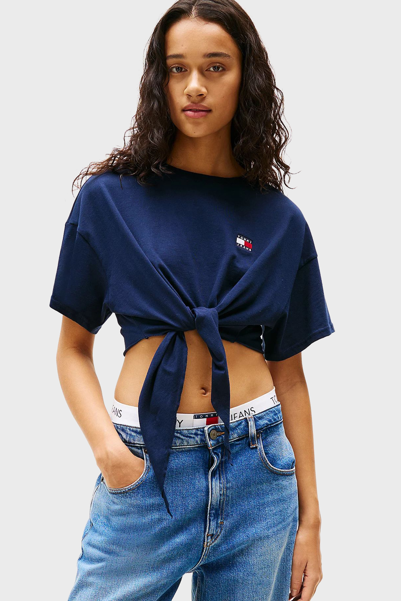 Женская темно-синяя футболка TJW REG WAIST TIE BADGE Синий XS Tommy Jeans DW0DW20321 Женская темно-синяя футболка TJW REG WAIST TIE BADGE Синий XS Tommy Jeans DW0DW20321